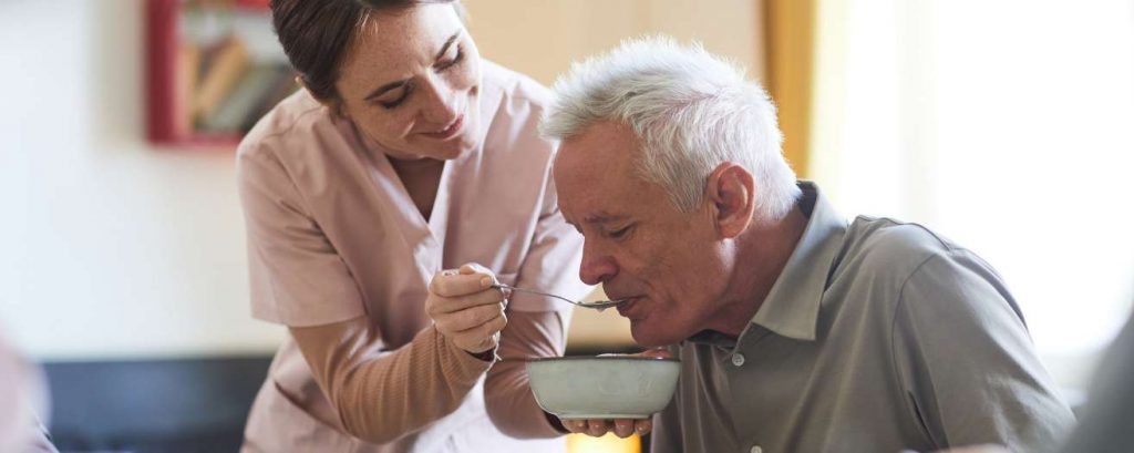 a care home worker assisting an elderly man with dementia