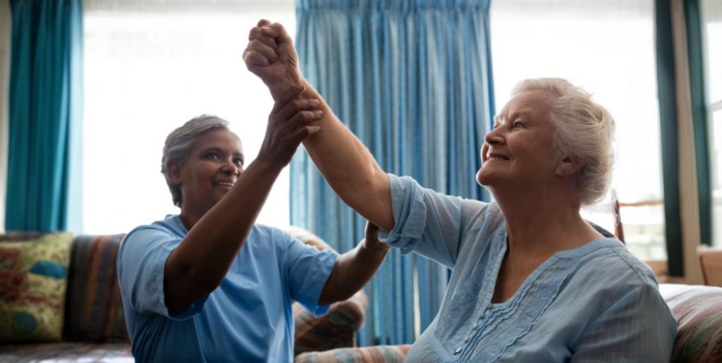 an elderly woman practicing mobility exercises with a care home worker who has received safeguarding training